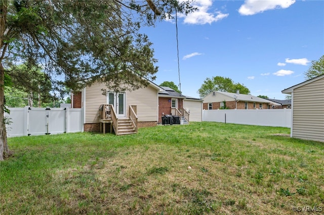 rear view of property featuring a lawn, a fenced backyard, a gate, and entry steps