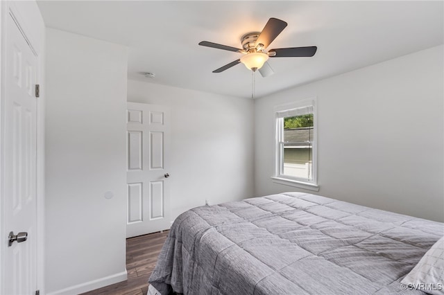 bedroom with dark wood-style flooring, a ceiling fan, baseboards, and a closet