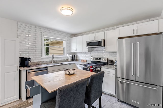 kitchen featuring a sink, appliances with stainless steel finishes, tasteful backsplash, and butcher block counters