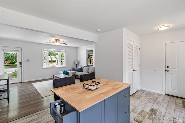 kitchen with light wood-type flooring, blue cabinets, baseboards, and wooden counters