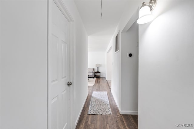 hallway with baseboards, wood finished floors, and visible vents