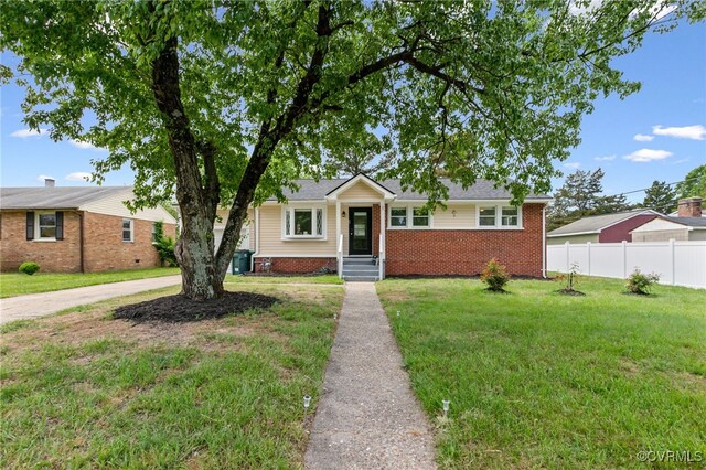 bungalow-style house featuring brick siding, fence, and a front lawn