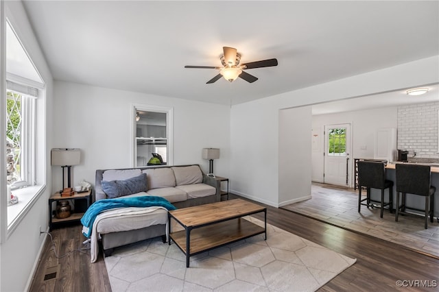 living area featuring baseboards, a ceiling fan, and wood finished floors