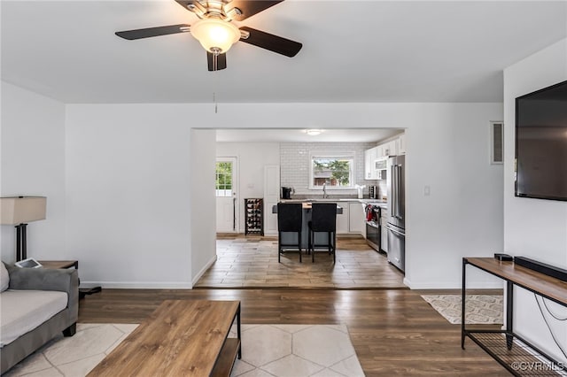 living area featuring a ceiling fan, visible vents, and wood finished floors