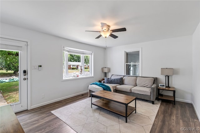 living room featuring plenty of natural light, light wood finished floors, ceiling fan, and baseboards