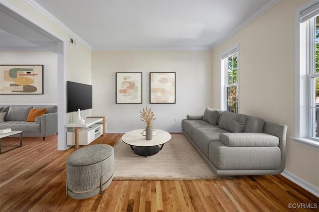 living room with visible vents, ornamental molding, wood finished floors, and a healthy amount of sunlight
