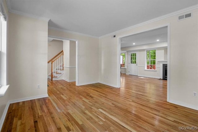 unfurnished room with visible vents, ornamental molding, stairs, baseboards, and light wood finished floors