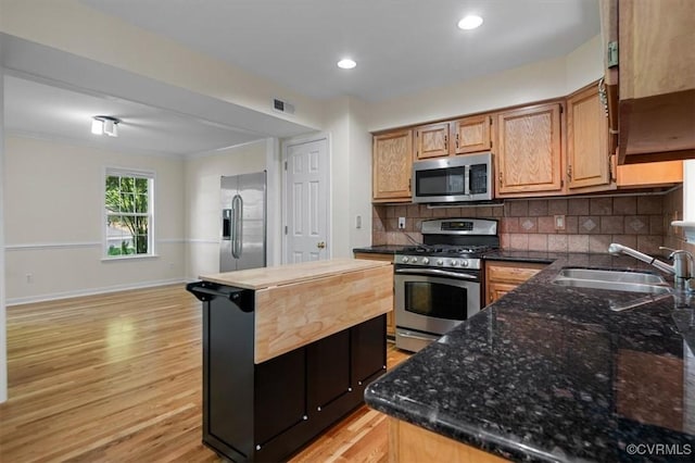 kitchen with visible vents, a sink, light wood-style flooring, appliances with stainless steel finishes, and backsplash