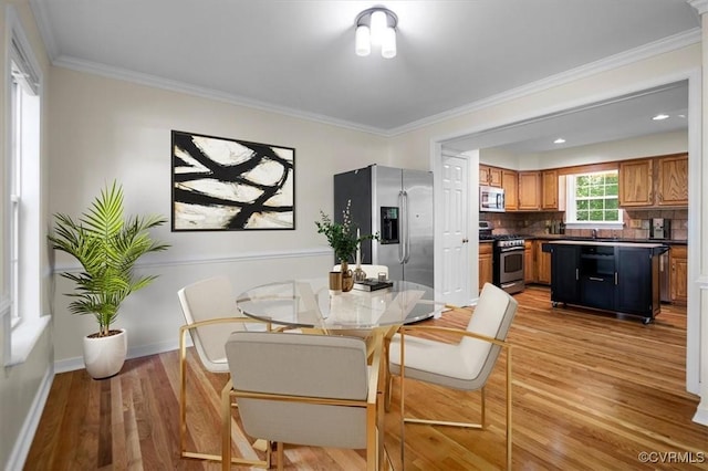 dining room featuring light wood-style floors, ornamental molding, and baseboards