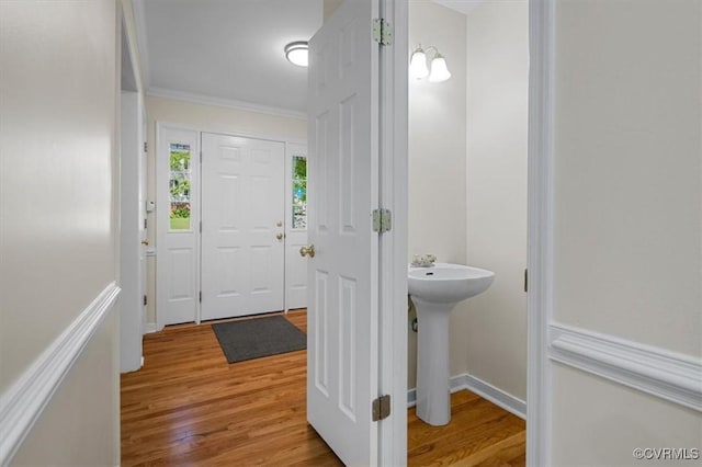 bathroom featuring baseboards, a sink, wood finished floors, and ornamental molding