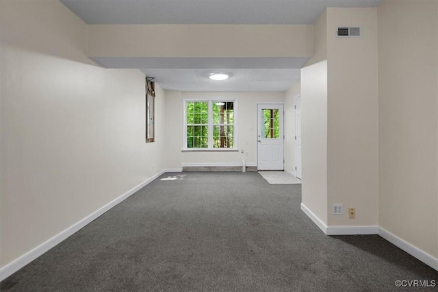 spare room with dark colored carpet, baseboards, and visible vents