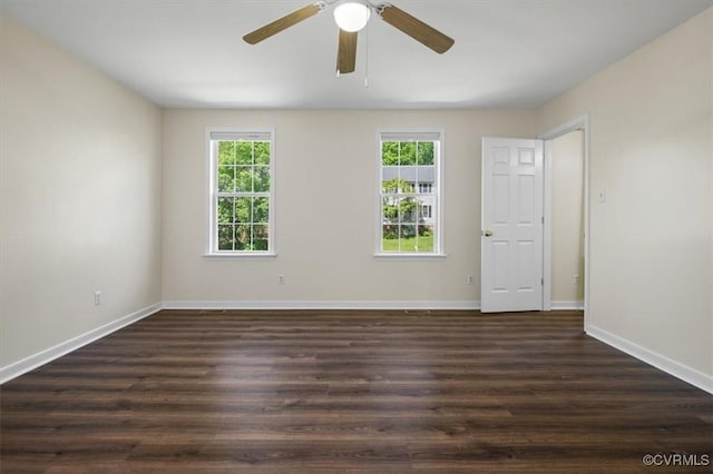 spare room featuring a ceiling fan, baseboards, a wealth of natural light, and dark wood-type flooring