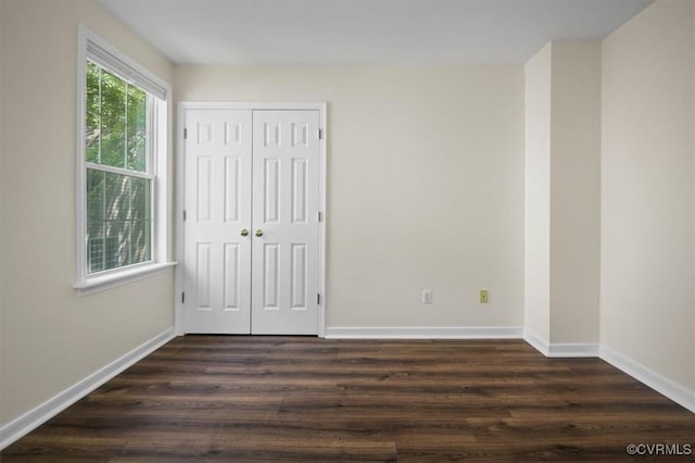 unfurnished bedroom with baseboards, a closet, and dark wood finished floors