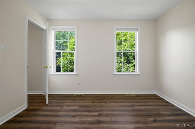 empty room with baseboards, plenty of natural light, and dark wood-type flooring
