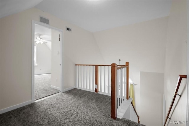 corridor featuring visible vents, baseboards, carpet, vaulted ceiling, and an upstairs landing