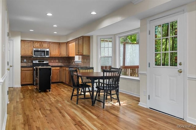 kitchen with dark countertops, stainless steel microwave, gas range oven, and plenty of natural light