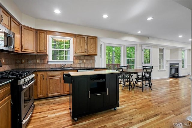 kitchen with a kitchen island, stainless steel appliances, a sink, and light wood finished floors