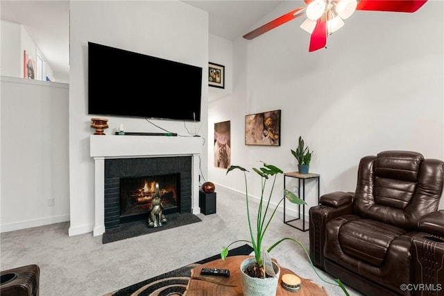carpeted living room with a ceiling fan, baseboards, and a fireplace with flush hearth