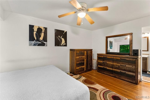 bedroom featuring a ceiling fan, connected bathroom, and wood finished floors