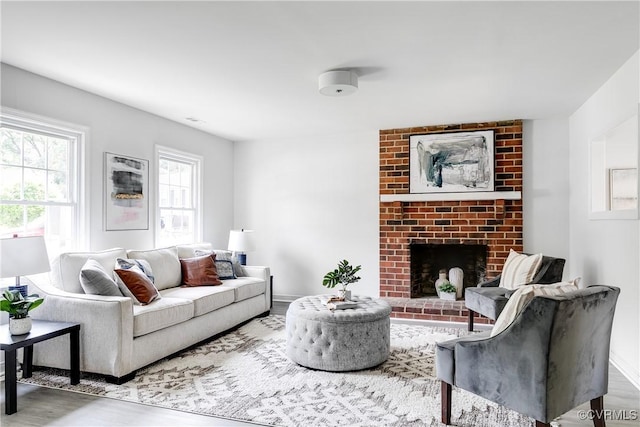 living room featuring a brick fireplace and wood finished floors