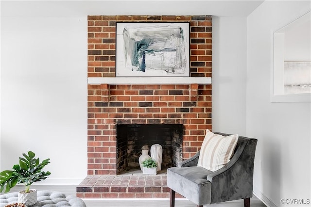 interior details with baseboards, a brick fireplace, and wood finished floors