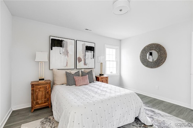 bedroom featuring baseboards, wood finished floors, and visible vents
