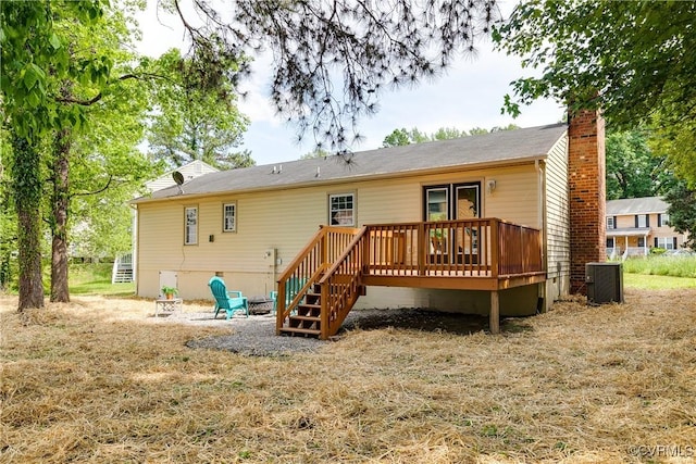 rear view of house with stairway, a deck, central AC unit, and a chimney