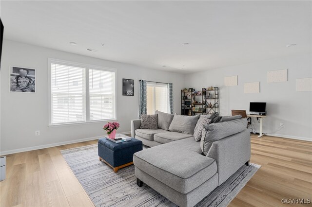 living area with baseboards, light wood-style flooring, and visible vents