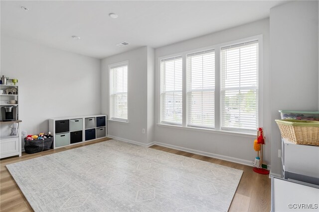 living area featuring baseboards, visible vents, and light wood finished floors