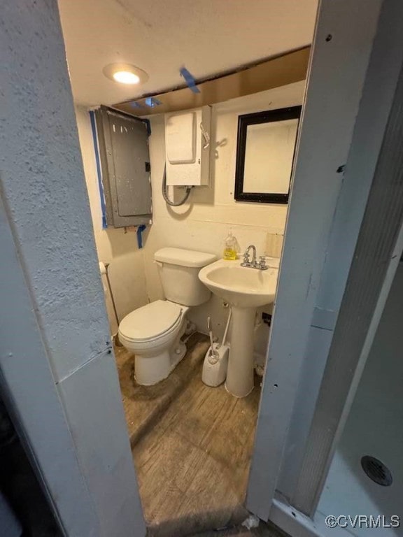 bathroom with a sink, electric panel, and toilet