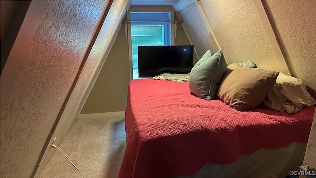 carpeted bedroom featuring a textured wall and vaulted ceiling