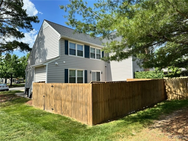 view of home's exterior featuring fence, a shingled roof, and a yard
