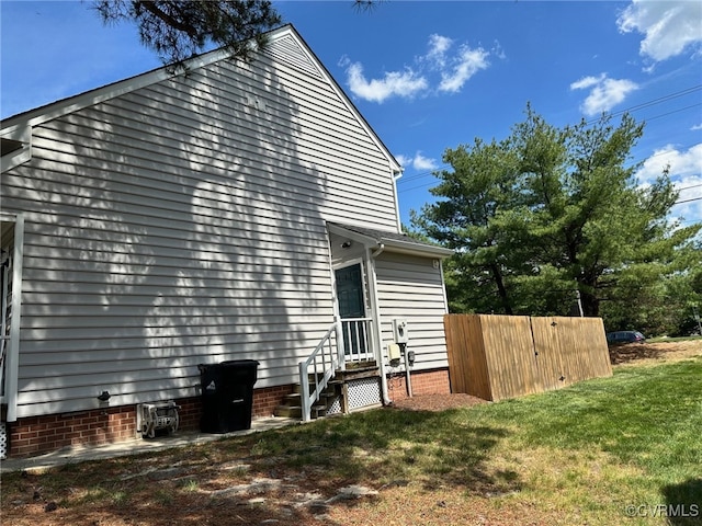view of side of home with a lawn, fence, and entry steps