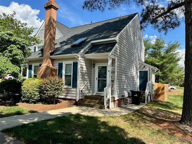 exterior space with roof with shingles, a front yard, and a chimney