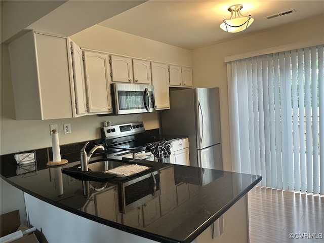 kitchen featuring a sink, stainless steel appliances, visible vents, and white cabinets