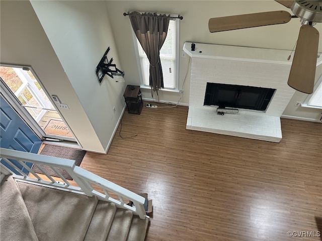 living room featuring a fireplace, baseboards, a healthy amount of sunlight, and wood finished floors