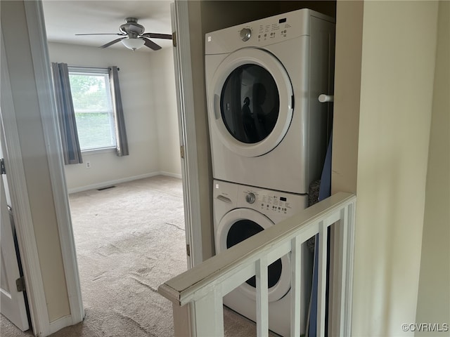 clothes washing area featuring baseboards, ceiling fan, stacked washer and clothes dryer, laundry area, and carpet floors