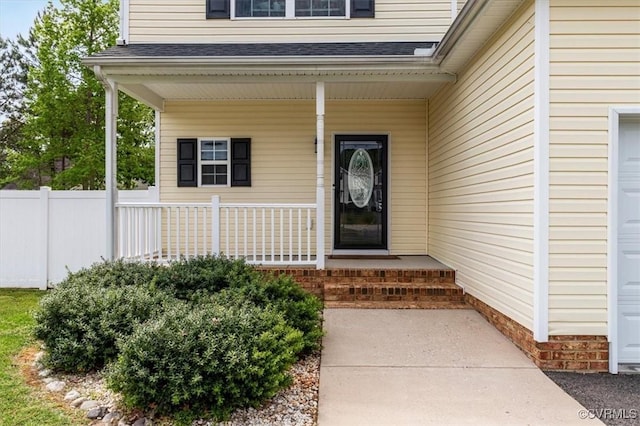 doorway to property featuring a porch, roof with shingles, and fence