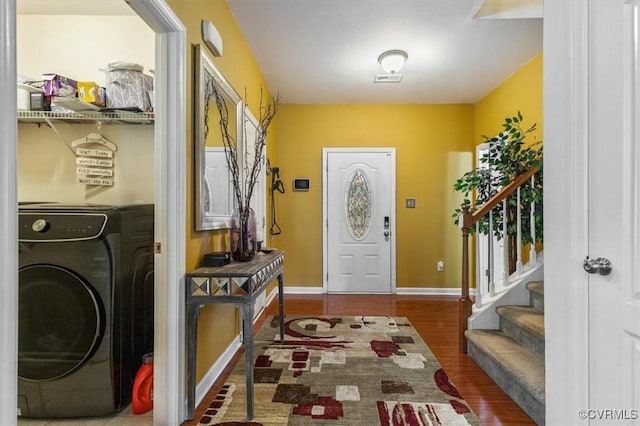 entryway with baseboards, washer / dryer, wood finished floors, and stairway