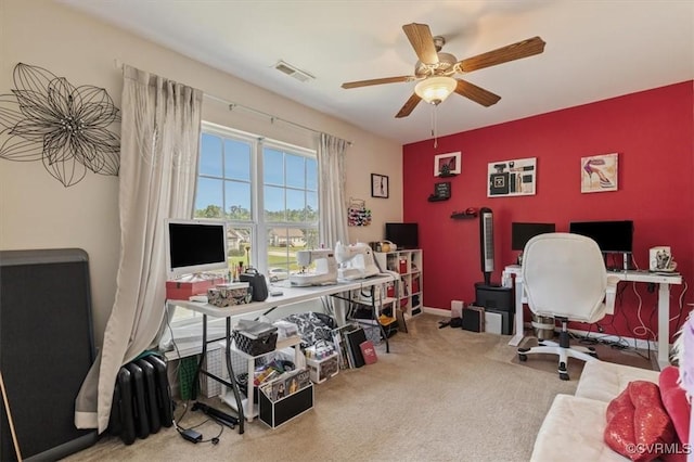 office space featuring carpet floors, an accent wall, a ceiling fan, and visible vents