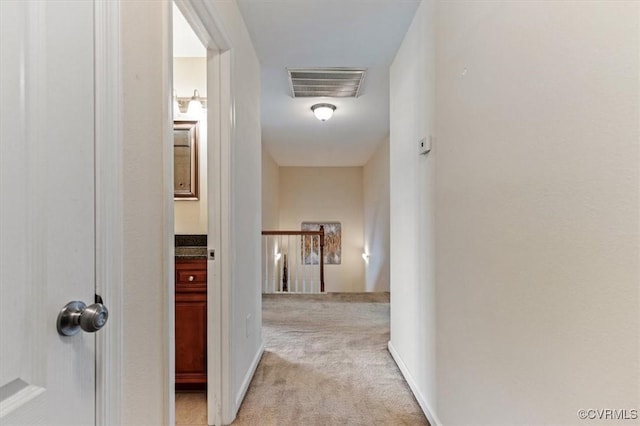 hallway featuring visible vents, carpet flooring, and an upstairs landing