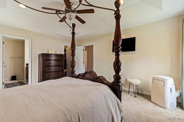 bedroom with baseboards, a ceiling fan, ensuite bath, and light colored carpet