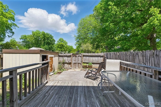 deck with a fenced backyard, an outbuilding, and a storage shed