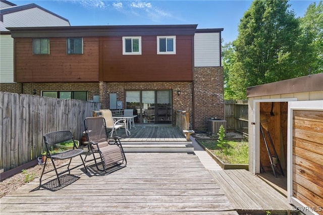 wooden terrace with central AC, a fenced backyard, and outdoor dining space