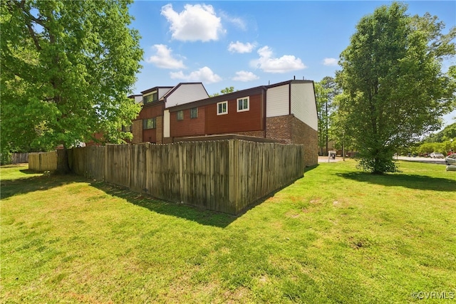 back of house featuring a yard, brick siding, and fence