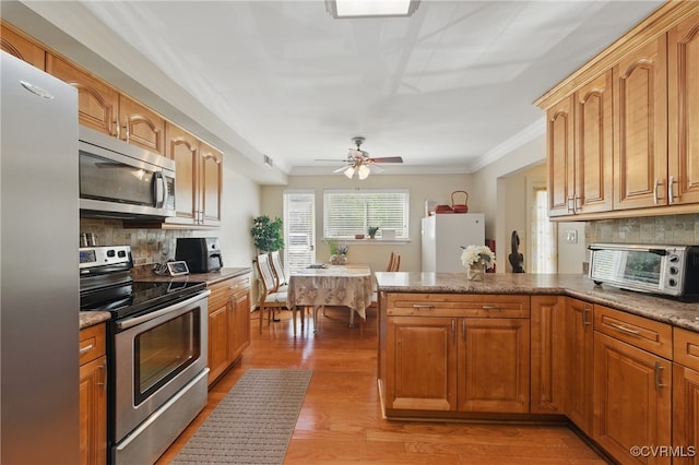 kitchen with decorative backsplash, ornamental molding, stainless steel appliances, and a peninsula