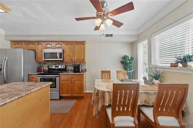 kitchen with visible vents, decorative backsplash, crown molding, light wood-style flooring, and stainless steel appliances