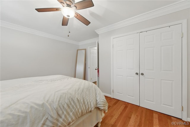 bedroom featuring a ceiling fan, crown molding, light wood-type flooring, baseboards, and a closet