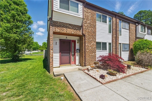 multi unit property with a front yard and brick siding