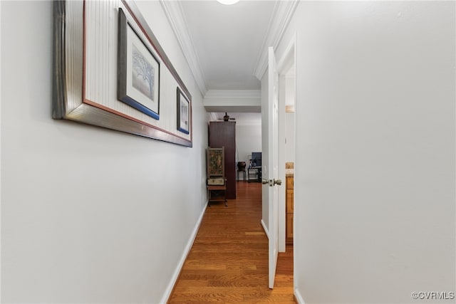 corridor with baseboards, ornamental molding, and light wood-type flooring